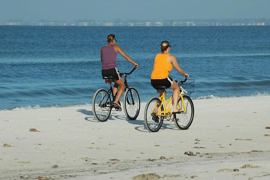 Two people riding bikes on beach