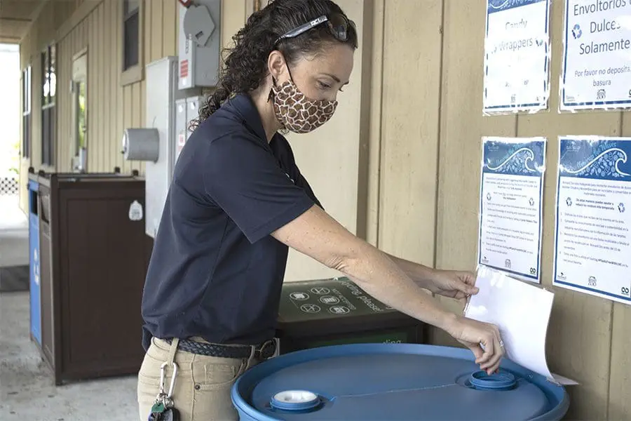 Amy places candy wrappers in recycling receptacle