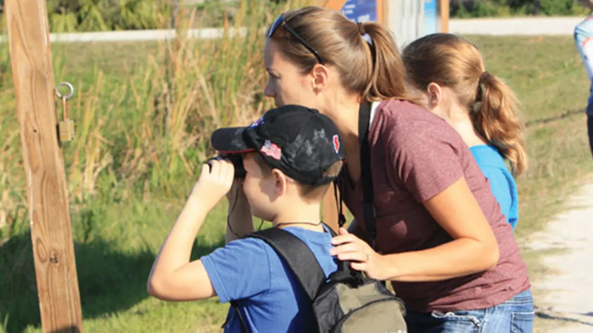 boy with binoculars with his family looking out into the wetlands