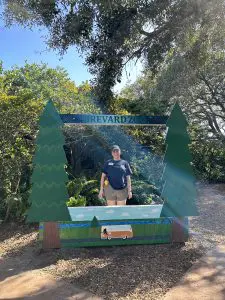 A woman stands behind a photo-op cut out display which reads "BREVARD ZOO"