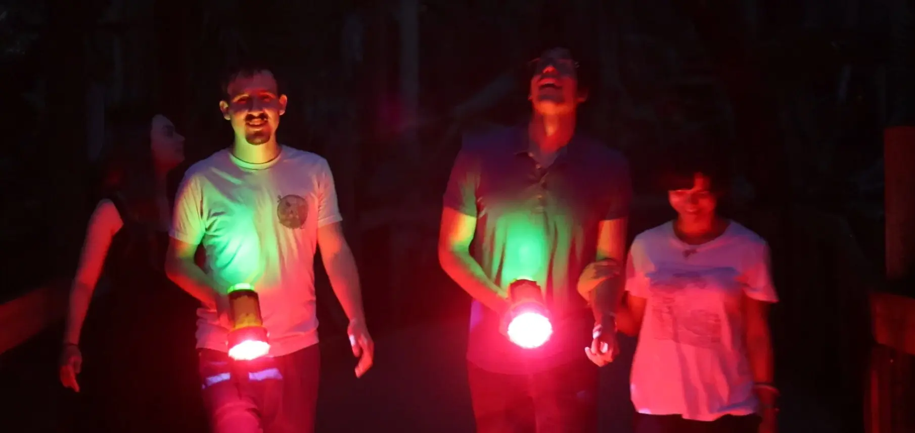 young adults with flashlights exploring the walkway at the zoo at night