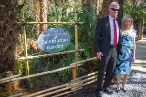 Sponsor poses by Celebration Garden sign