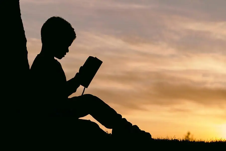 Silhouette of child reading outside