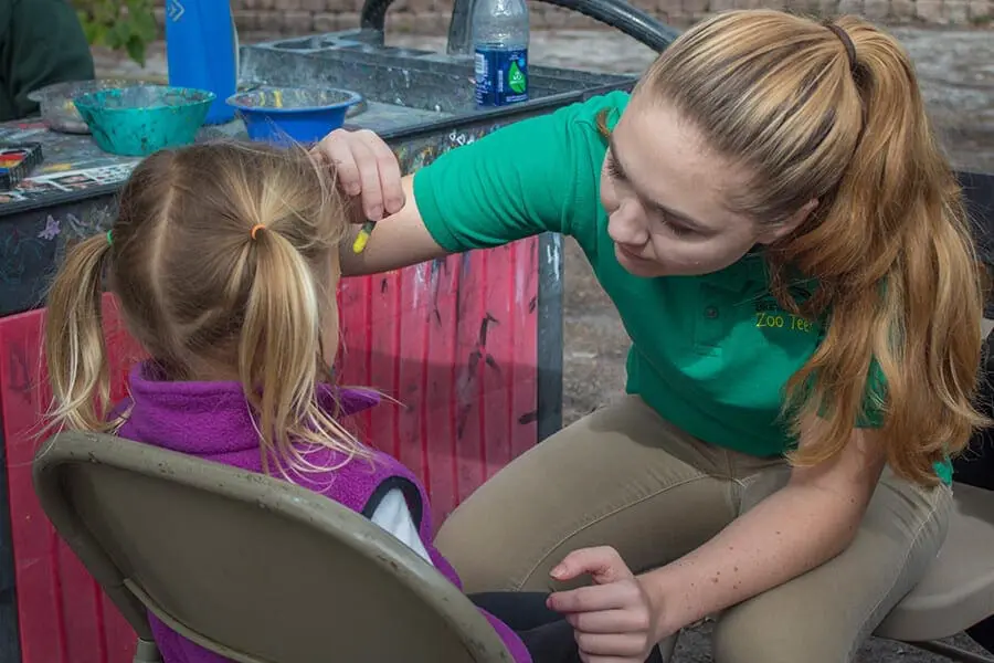 Zoo teen Haven painting the face of a young Zoo guest