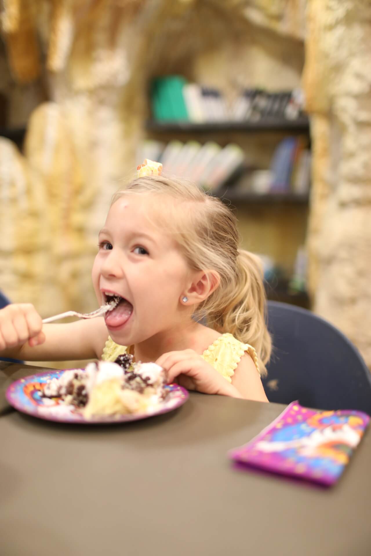 Girl excitedly eats a piece of birthday cake.