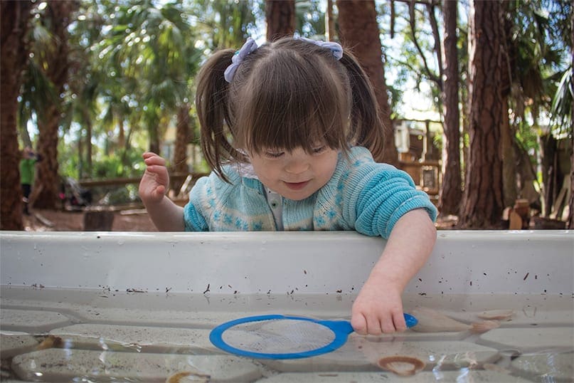 A girl puts her hand in an educational water experience.