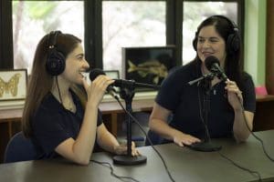 Bri Wright and Lauren Delgado pose for a photo with podcasting equipment