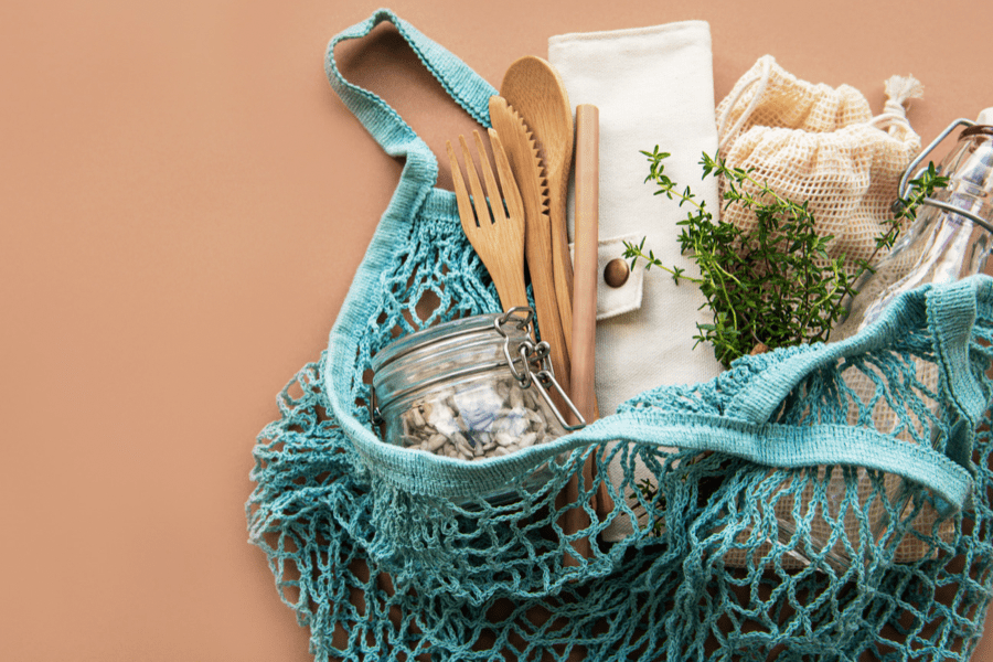 A mesh bag containing a jar, wooden utensils, and more.