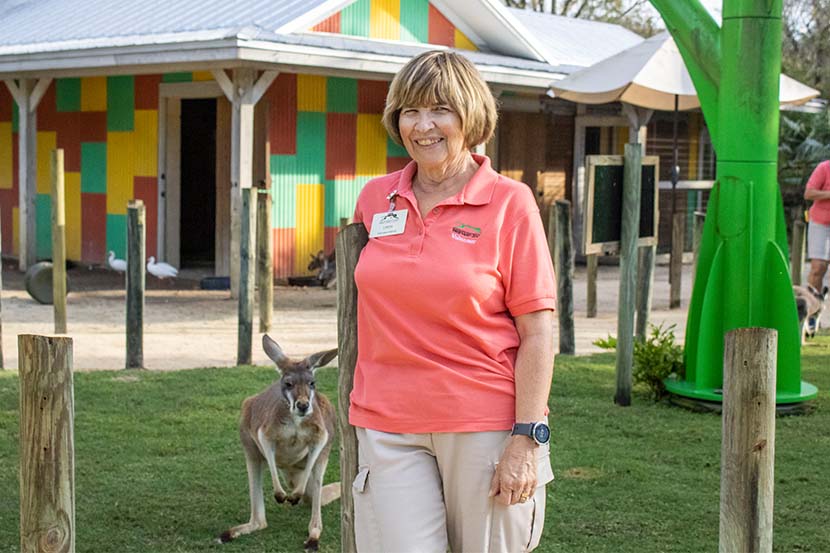 Female volunteer stands in front of a kangaroo.