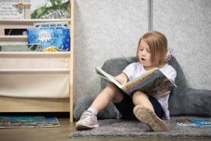 A preschooler reads a dinosaur book.