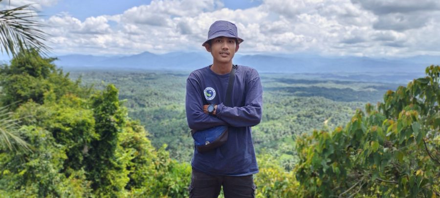 A member of the Sumatran Ranger Project stands with mountains in the background.