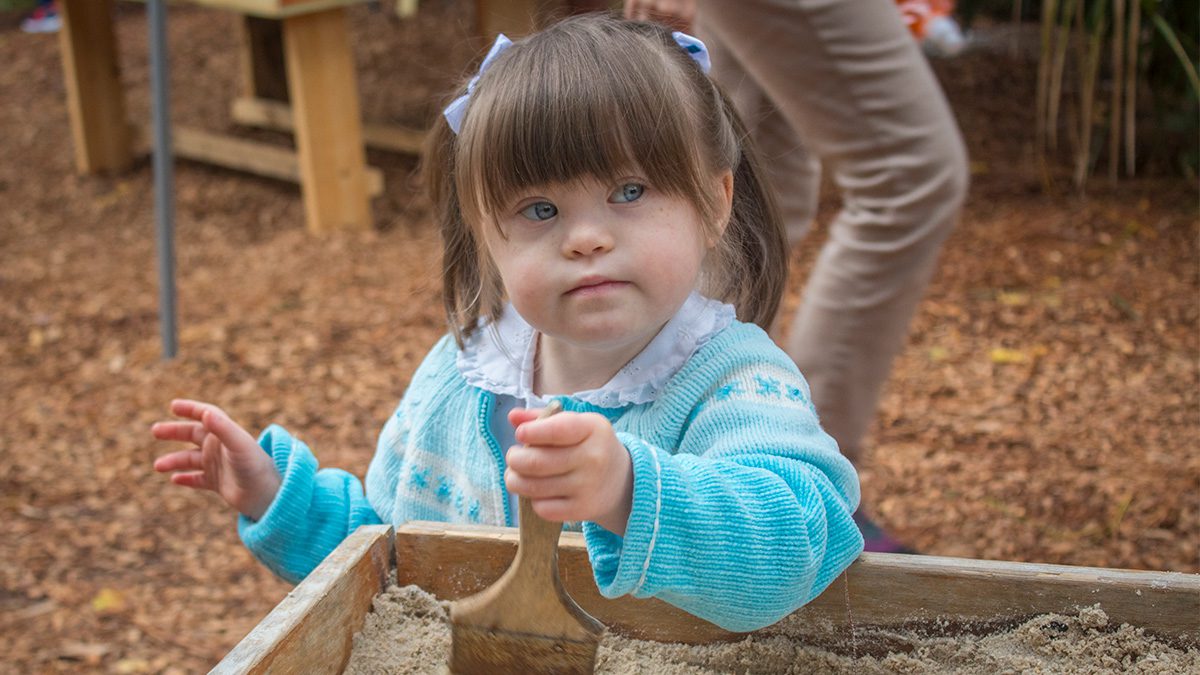 young girl in exceptional nature space using paint brush to gently reveal sandbox treasures