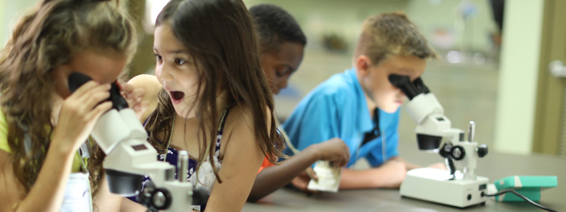 kids looking through microscopes excitedly