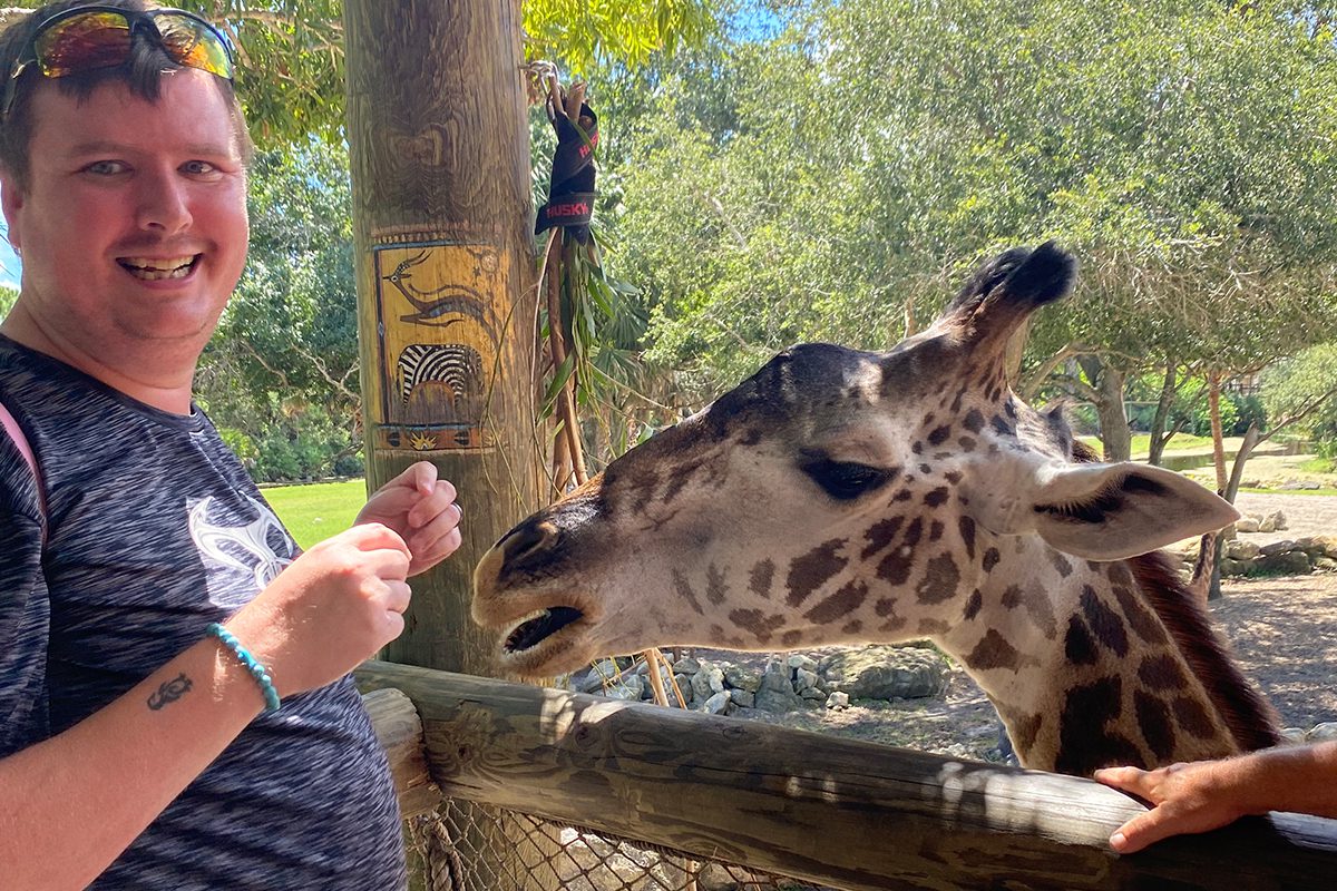 smiling man feeding giraffe