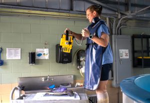 A woman stands over a sea turtle with a portable x-ray machine to take an image of them.