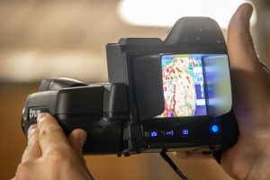 A veterinarian holds up a camera to get a thermographic image of a giraffe