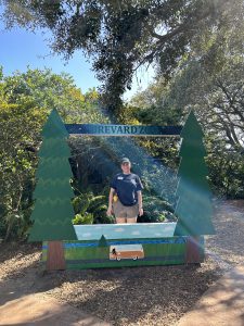 A woman stands behind a photo-op cut out display which reads "BREVARD ZOO"