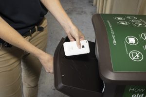 A woman tosses an iPhone into a recycling bin.