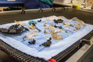Several pieces of plastic are laid out on a towel upon a table.