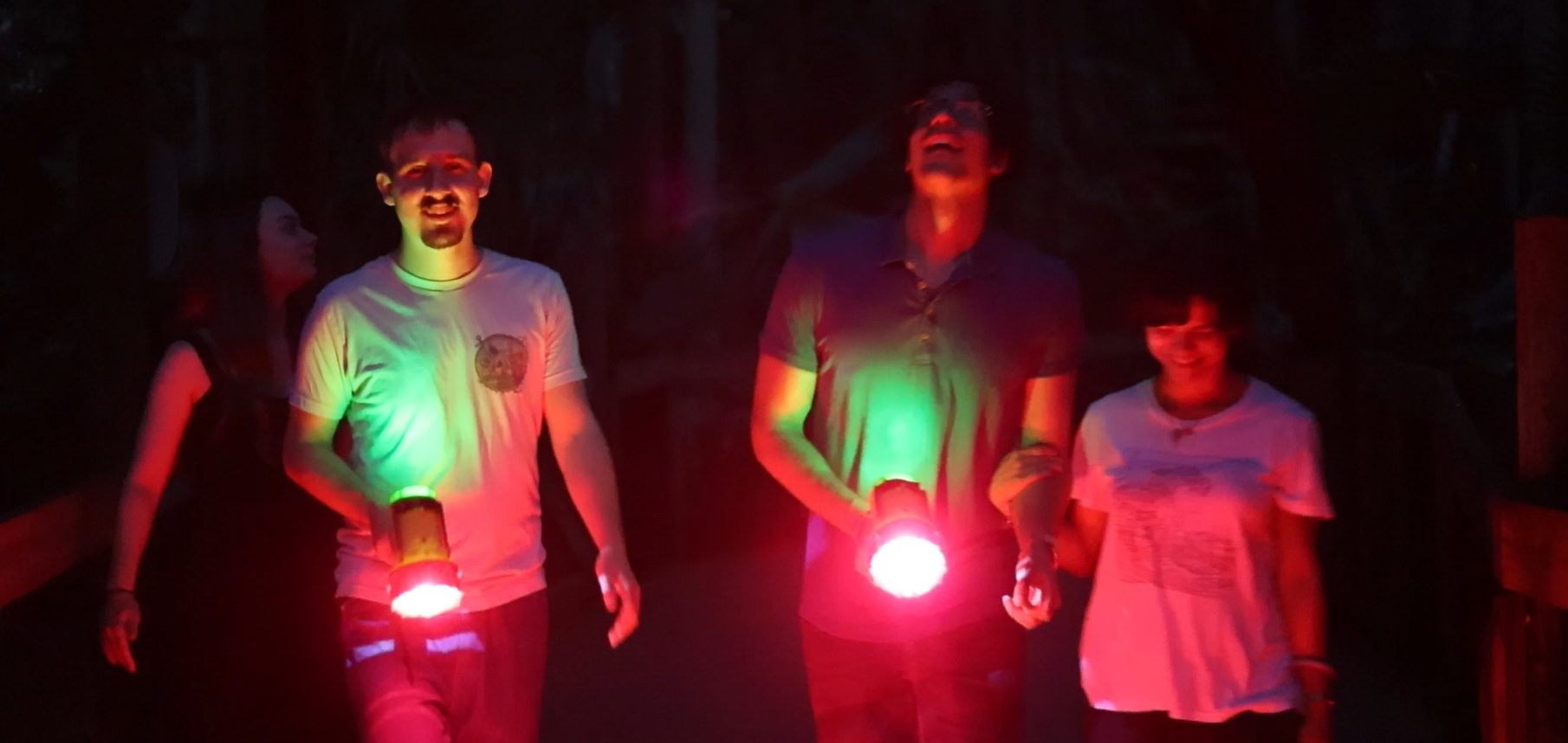 young adults with flashlights exploring the walkway at the zoo at night