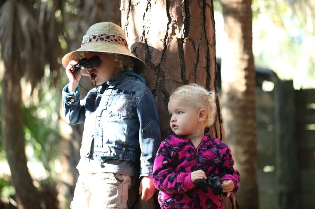 Young siblings lean against a tree