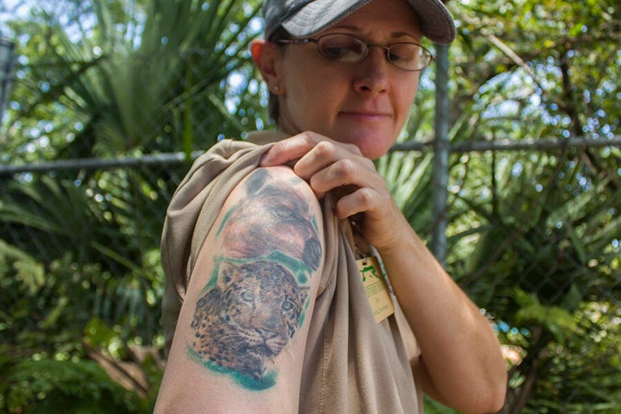 Zookeeper Em showing her arm tattoo with animals